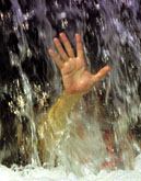 A photo of a hand from behind the dam's water fall.